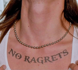 A person with a tattoo spelt as “NO RAGRETS” across their chest.