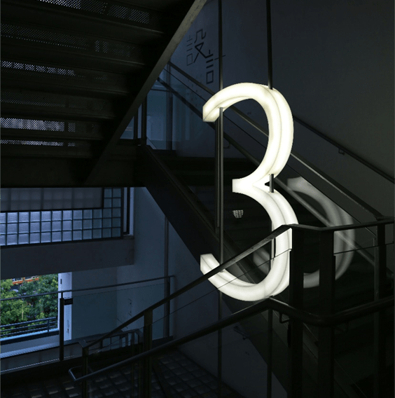 A picture of a dark stairwell with an illuminated 3 hanging light to indicate the 3rd floor